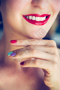 白的漂亮女人带着红色的口和白牙彩色的指甲油正在照镜子背景图片