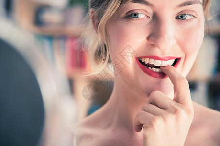 白的漂亮女人带着红色的口和白牙彩色的指甲油正在照镜子图片