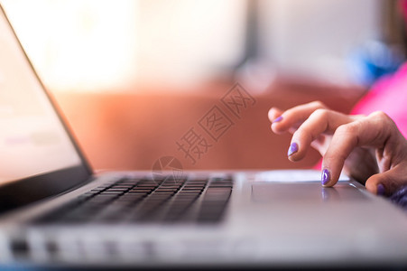 穿紫色指甲的女孩在沙发上家里用笔记本电脑图片