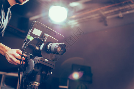 男摄影师正在电视演播室操作一部电影摄机图片