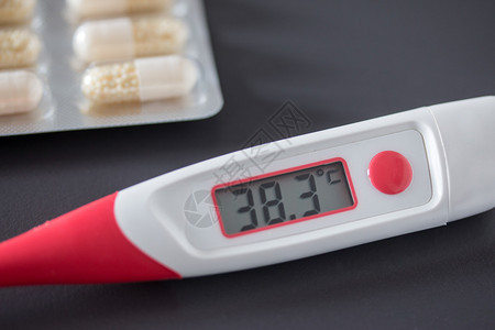 红色热温度计桌上有数字显示器和药丸图片