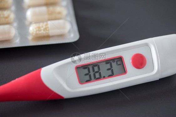 红色热温度计桌上有数字显示器和药丸图片