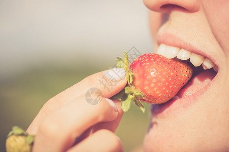 女人把成熟的有机草莓放进嘴里闭上白牙图片