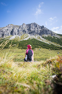 穿运动服的妇女正在徒步时休息坐在地上享受山和湖风景图片