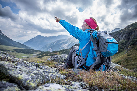 背的登山者坐在石土地上做一个指尖手势图片