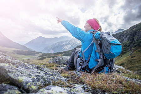 背的登山者坐在石土地上做一个指尖手势图片