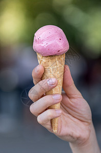 女人手里握着草莓冰淇淋阳光明媚的夏日模糊背景图片