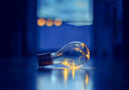 LED灯泡躺在木制地板上是思想和创新的标志是模糊背景中的窗口和灯光图片