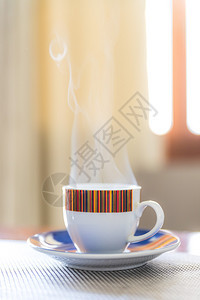 早上端的意大利奶油咖啡小杯可爱的意大利咖啡蒸汽着图片