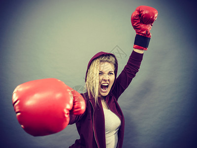身戴红拳击手套打赢比赛鼓动感到轻松和幸福的运动妇女图片
