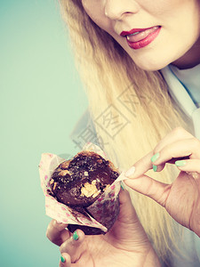 迷人的金发美女手握着味的巧克力蛋糕渴望美味的甜点迷人女子手握着蛋糕图片