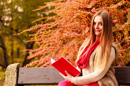 秋天公园时装女郎在秋天公园放松坐在长凳上读书秋天生活方式概念秋天公园女郎在季放松阅读书图片