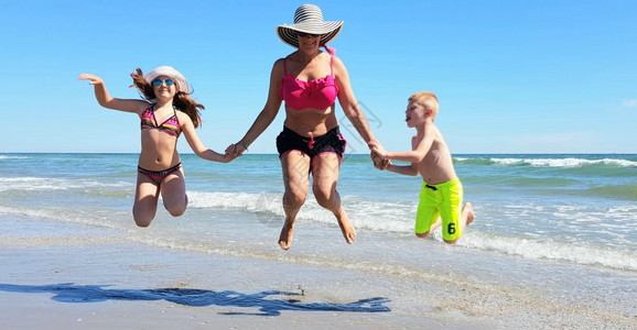 母亲和孩子在海滩上跳跃图片