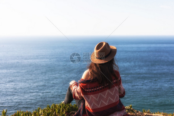 穿着旅行服和帽子坐着看蓝色的海洋和天空旅行概念照片穿旅行服和帽子坐着看蓝色的海洋和天空图片