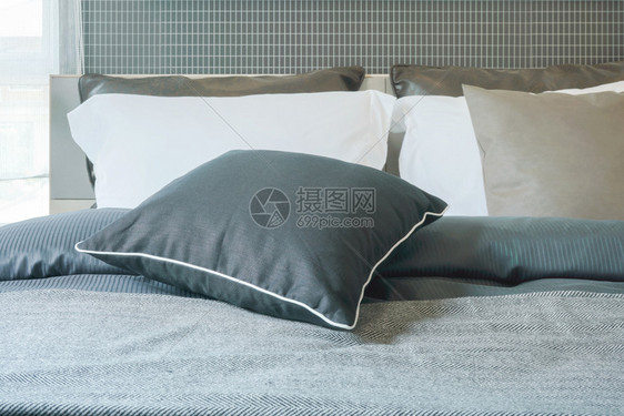 在现代室内卧的时尚床铺上紧贴黑色枕头的图片