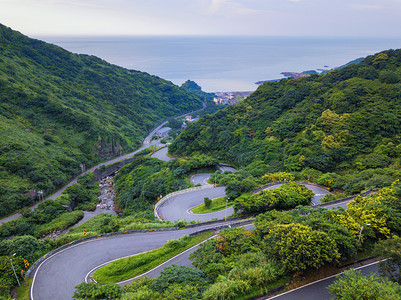 台新北市农村地区绿色天然林的汽车在弯曲齐格扎公路或山街上行驶的空中景象图片