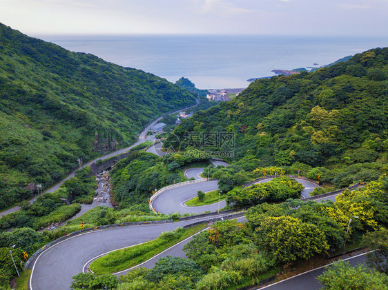 台新北市农村地区绿色天然林的汽车在弯曲齐格扎公路或山街上行驶的空中景象图片