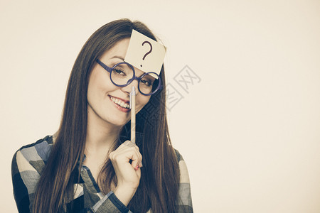 女迷惑思考寻求解决方案纸牌上写有问号眼镜制片厂的可疑年轻女拍摄了刻度图像女在头部上写着问号图片