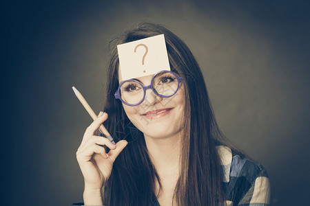 女困惑的思考寻求解决方案纸牌上写着问号头部有眼镜制片厂的可疑年轻女被黑人拍到女在头部上写着问号图片