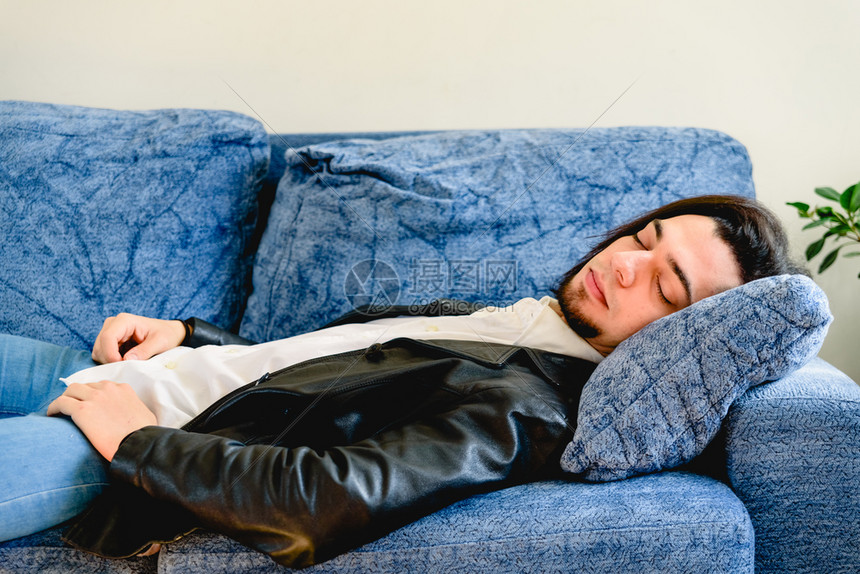躺在沙发上休息家中的年轻男子疲劳累偏头痛