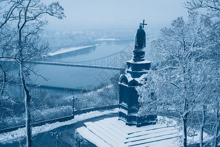 基辅圣沃洛季米尔冬的白化青铜雕像底的冷冻Dnieper河和足桥图片