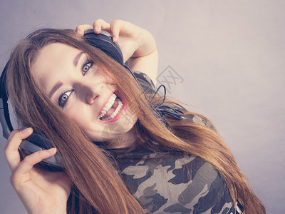 年轻女孩通过大耳机听音乐玩得很开心背景图片