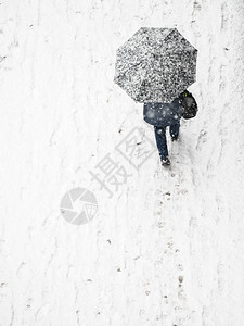 在冬季寒雪天气中人们在城市街道上行走时从到在城市街道看到冬季人们穿过铺盖在白雪中的人面上盖着保护伞冬天用雨的人面背景图片