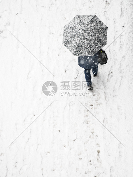 在冬季寒雪天气中人们在城市街道上行走时从到在城市街道看到冬季人们穿过铺盖在白雪中的人面上盖着保护伞冬天用雨的人面图片