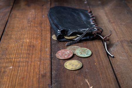 旧的皮革海盗钱包一个袋子里面装着小铜币躺在黑木质表面旧的海盗钱包图片