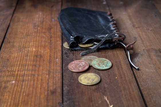 旧的皮革海盗钱包一个袋子里面装着小铜币躺在黑木质表面旧的海盗钱包图片