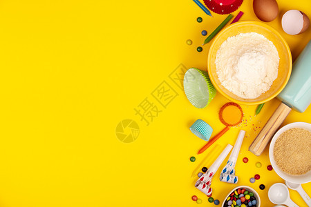 烘烤生日蛋糕的背景框架成分烘烤用的厨房品蜡烛厨房用具面粉鸡蛋糖文本空间顶部视图烘烤生日蛋糕成分在黄色背景上平铺图片