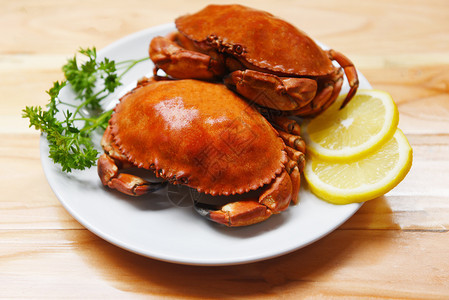 盘子里的煮蟹和柠檬药草以及木制餐桌的香料背景海产食品煮红石蟹沙拉图片