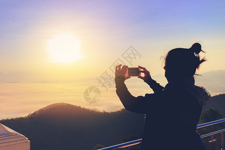 年轻女摄影师在山上拍照冬天更雾图片