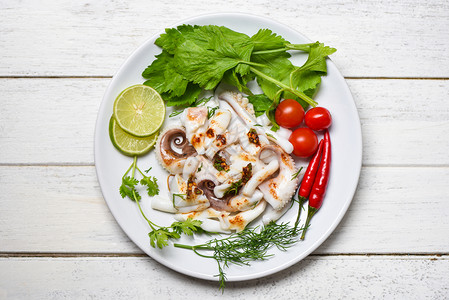 鱿鱼沙拉加柠檬药草和木制背景最上观的香料塔克莱章鱼煮开胃菜热辣酱海鲜在餐厅煮白盘上图片