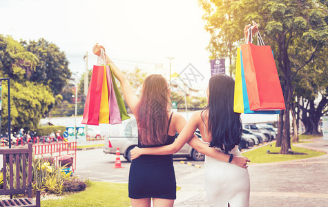 两名美丽的亚洲妇女在户外购物市场拿着袋图片