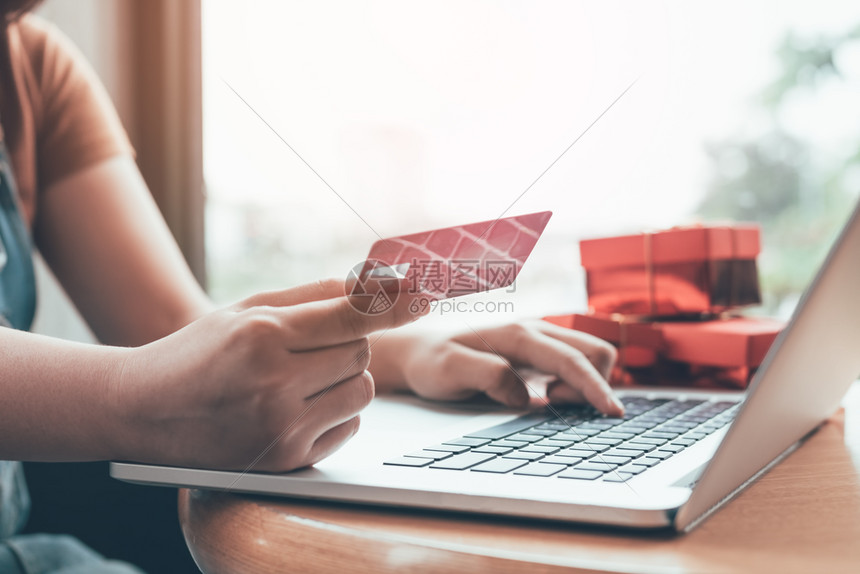 近身手持信用卡和打笔记本电脑键盘并带有网上购物概念图片