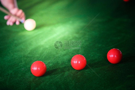 Man手和Cue臂在玩Snooker游戏或准备在绿色球桌上绿色盘上有多彩的Snooker球图片