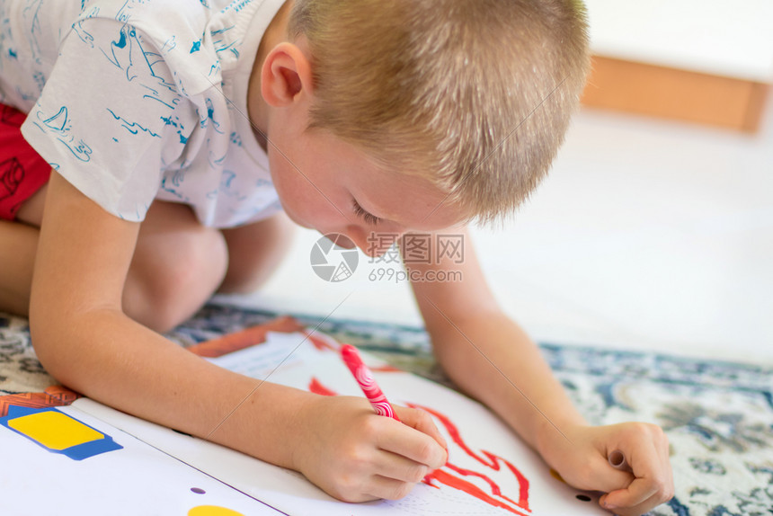 小男孩在白纸上用铅笔画图片
