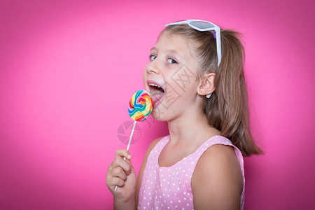 带着甜棒糖的笑孩子快乐与多彩粉红背景欢乐图片