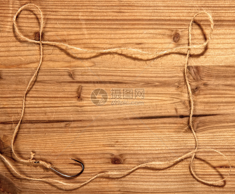 经典的大型钓鱼钩上面绑着粗糙的绳索在木制背景上形成一个简单的框架图片