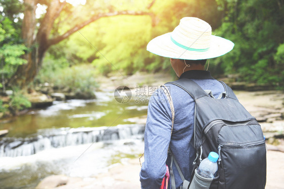 在森林冒险旅行游体育活动概念中男子徒带着背和瀑布行走的山地自然图片