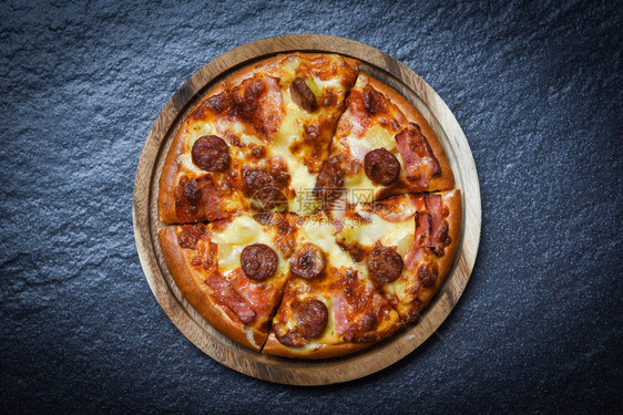 木盘上披萨切片美味可口的快餐意大利传统披萨奶酪和莫扎里拉熏猪肉香肠菠萝火腿酱图片