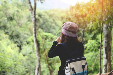 自然林旅行妇女度假旅行的女游客冒险旅行在树林中徒背包在山上观景点拍照图片