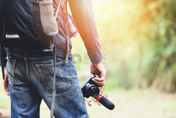 旅行者男子持有自然林旅游者在度假旅行时拍摄自然森林游客的相机冒险旅行在树林里徒步旅行在树林里背包图片