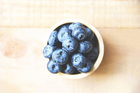 新鲜蓝莓水果在木桌背景的碗里图片