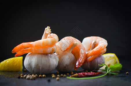 大蒜上的新鲜虾在盘子上海鲜煮开皮虾用辣椒柠檬和黑底煮熟的虾有选择地聚焦于图片