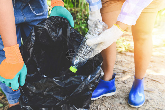 帮助保持自然清洁的青年妇女志愿者团体从有助于环境的公园回收和废物减少技术中拾取垃圾塑料瓶图片