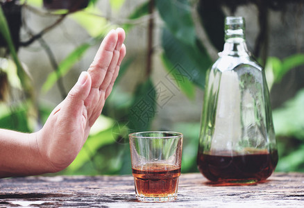 酒主图男人拒绝喝杯子和酒精饮料的手在户外桌边背景拒绝喝酒威士忌背景