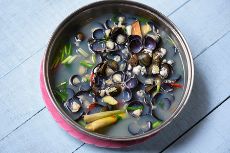 象用香草煮熟的蛤壳和木桌上碗汤的香料图片