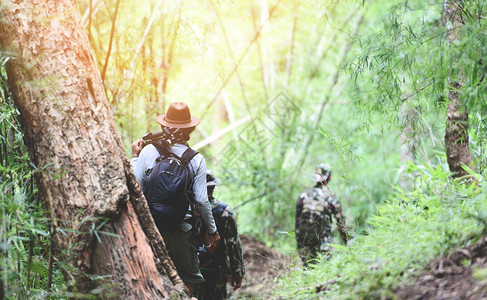 在竹林中行走的旅者男子登山上一群朋友带着背包和摄影器材走来去旅行游体育活动概念图片